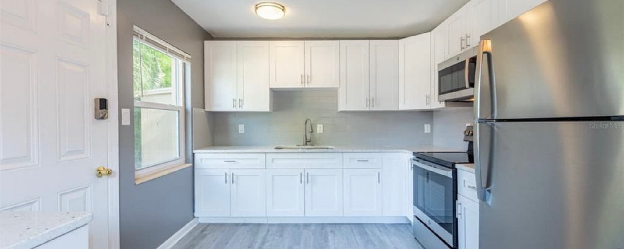 Renovated kitchen with white cabinets, new flooring, and updated appliances