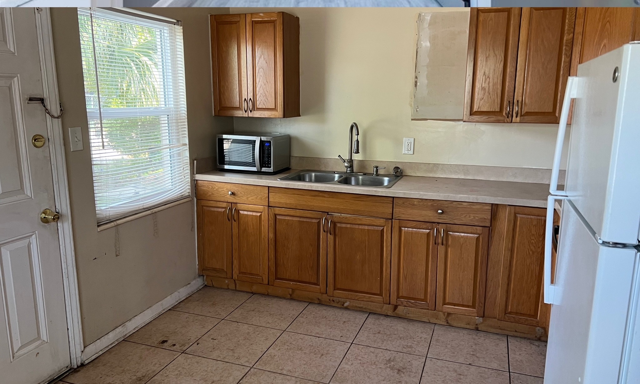 Kitchen before renovation, with wood cabinets, tile flooring, and older finishes